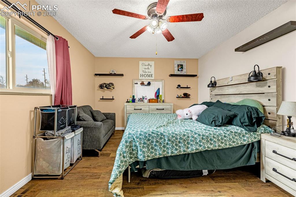 Image 19 of 29: Bedroom featuring wood finished floors, a ceiling fan, and a textured ceili