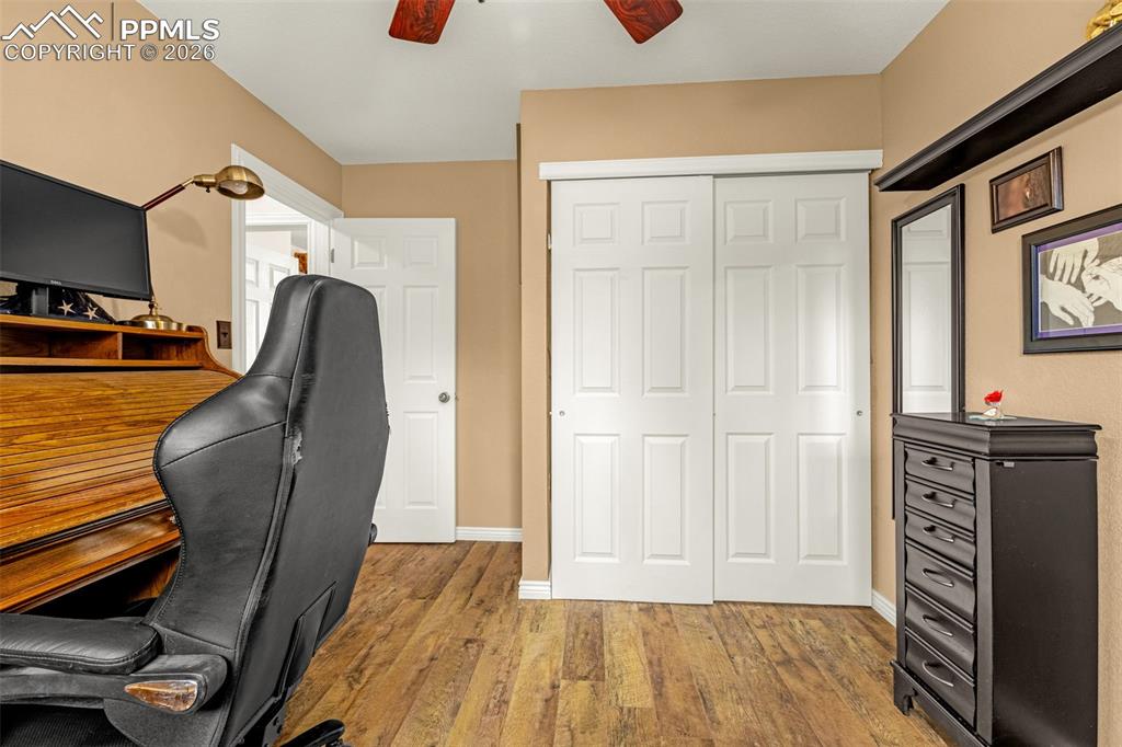 Image 23 of 29: Office area with a ceiling fan and wood finished floors