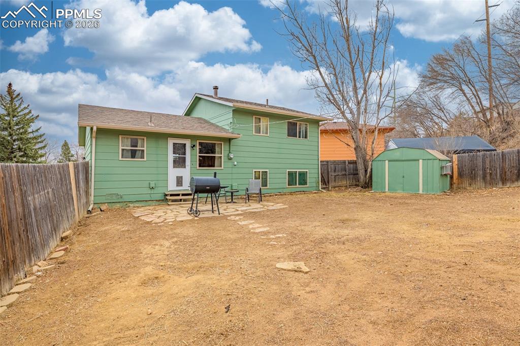 Image 27 of 29: Back of house with a fenced backyard, a patio, and a storage unit