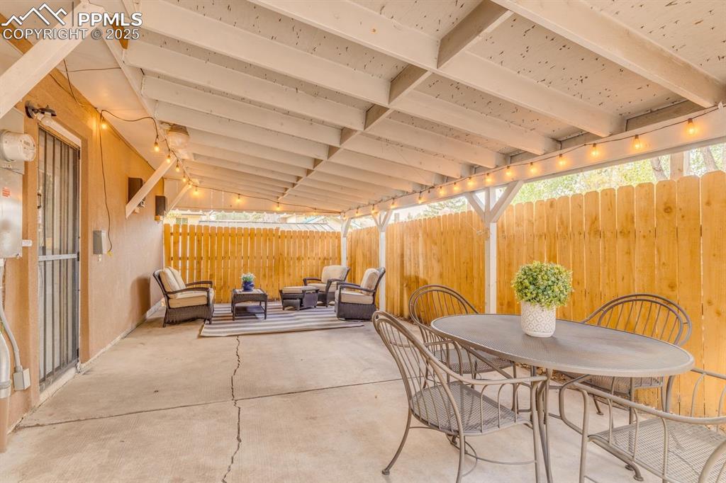 Image 12 of 47: Fenced backyard with a patio, outdoor dining area, and an outdoor hangout a