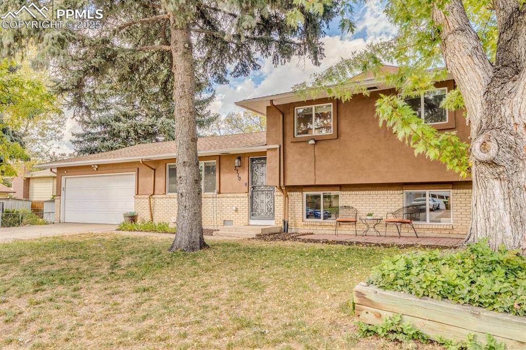 Image 17 of 47: Split level home featuring brick siding, a front lawn, driveway, and stucco