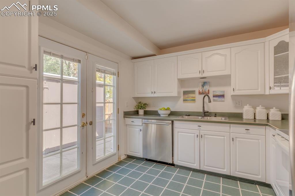 Image 34 of 47: Kitchen with white cabinets, dishwasher, white range oven, french doors, an