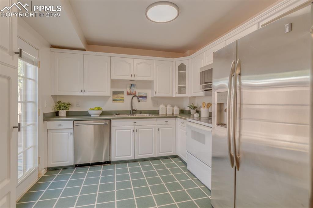 Image 35 of 47: Kitchen featuring stainless steel appliances, white cabinets, glass insert