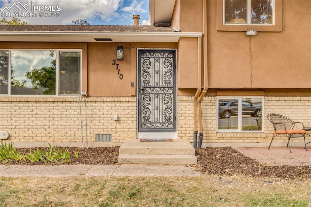 Image 42 of 47: Entrance to property featuring brick siding, stucco siding, and roof with s