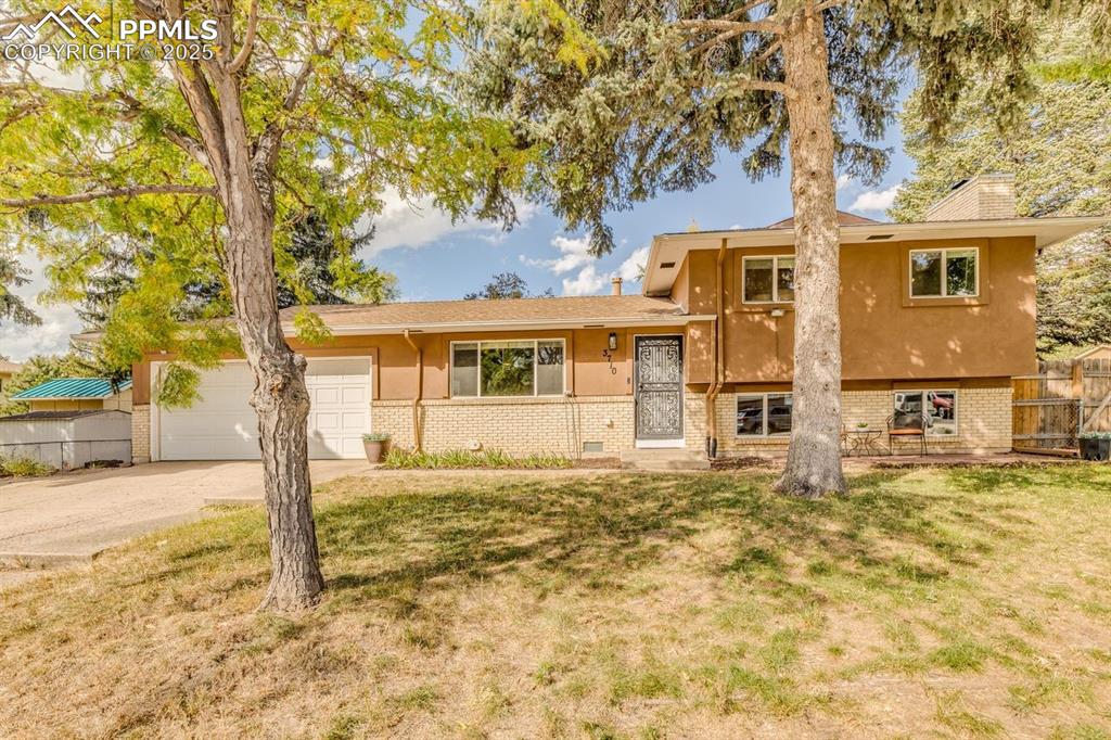 Image 43 of 47: Split level home with brick siding, concrete driveway, a garage, stucco sid
