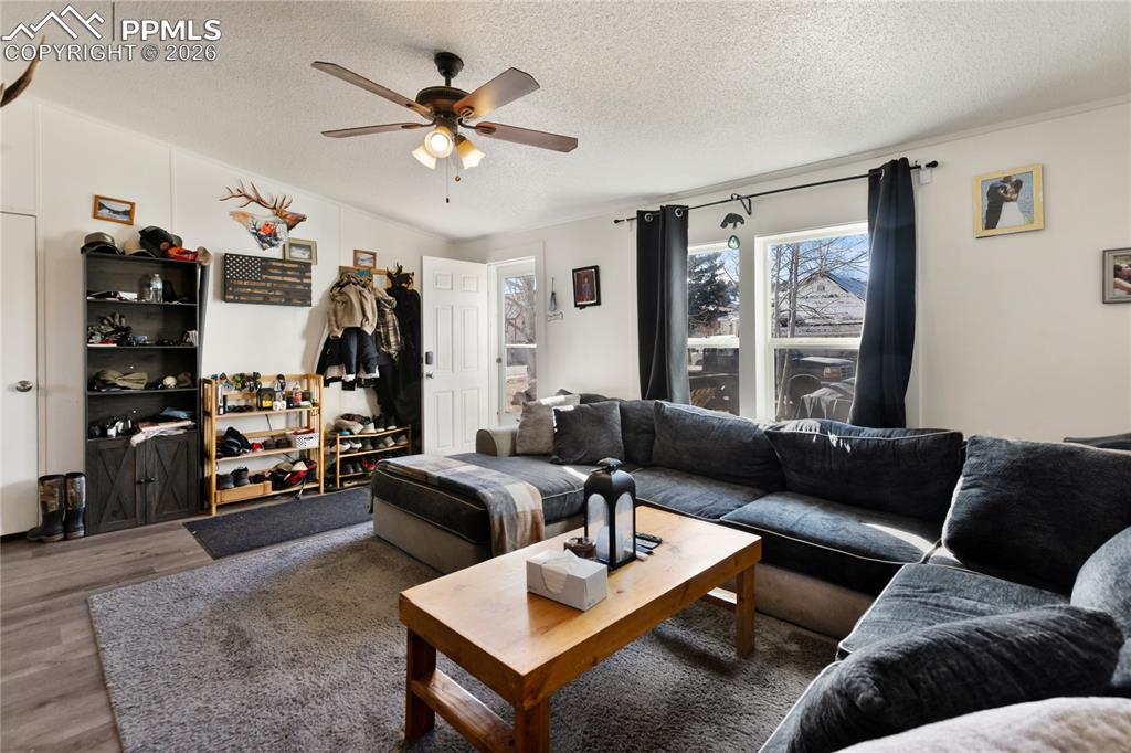 Image 11 of 27: The living area featuring wood finished floors, a textured ceiling, and a c