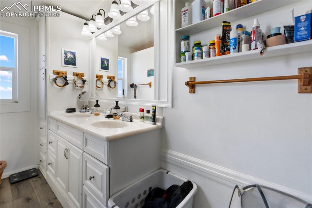 Image 12 of 27: The bathroom with double vanity and wood floors!