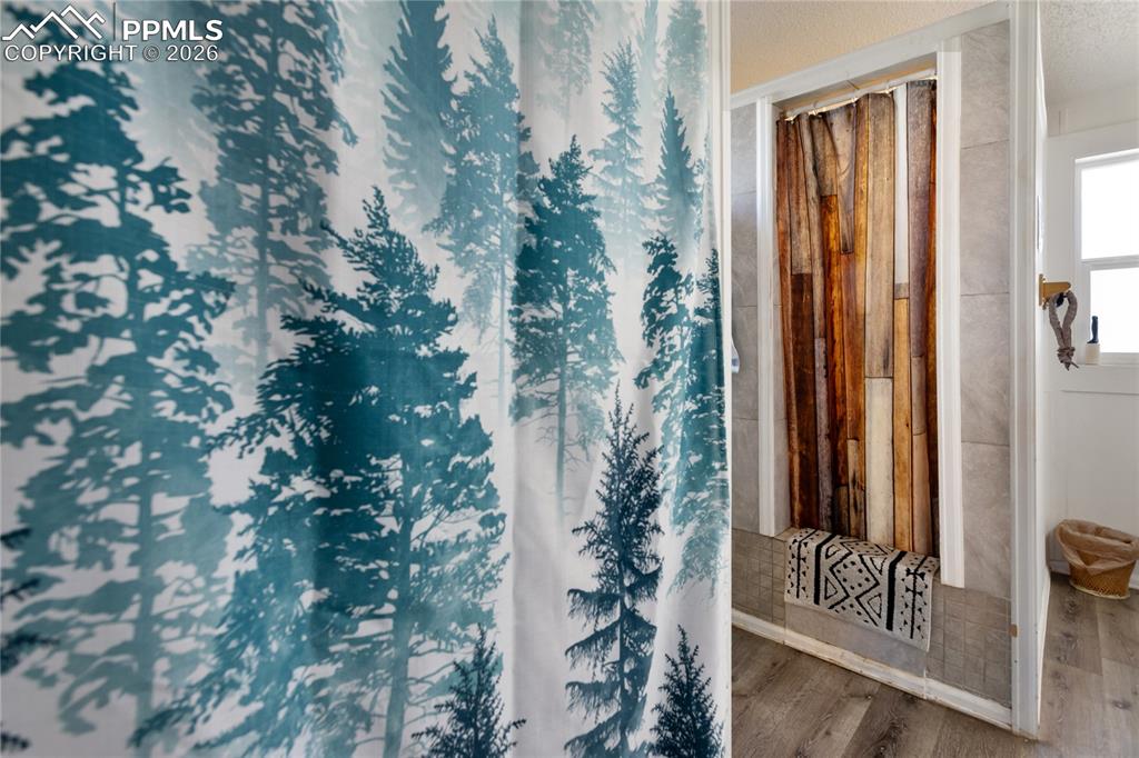Image 13 of 27: The full bath has a shower with curtain and wood floors!
