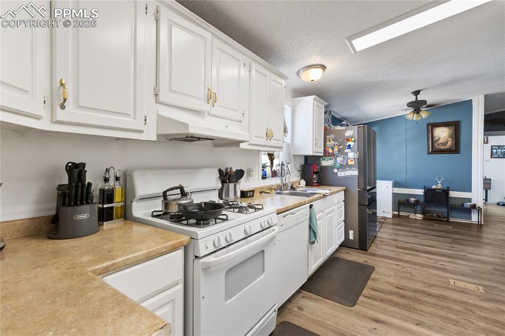 Image 5 of 27: Kitchen has white appliances, white cabinetry, light countertops, and light