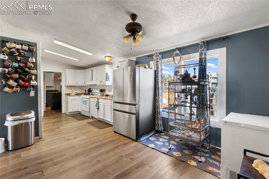 Image 6 of 27: The dining area overlooking the kitchen featuring freestanding refrigerator