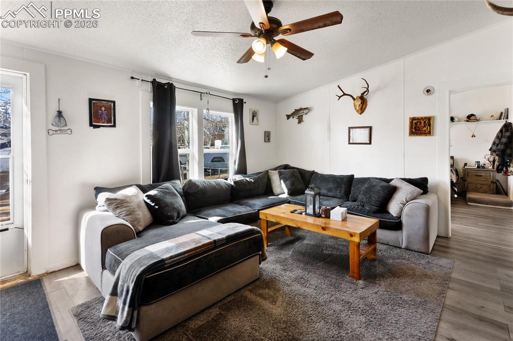 Image 9 of 27: The living area featuring wood finished floors, a ceiling fan!