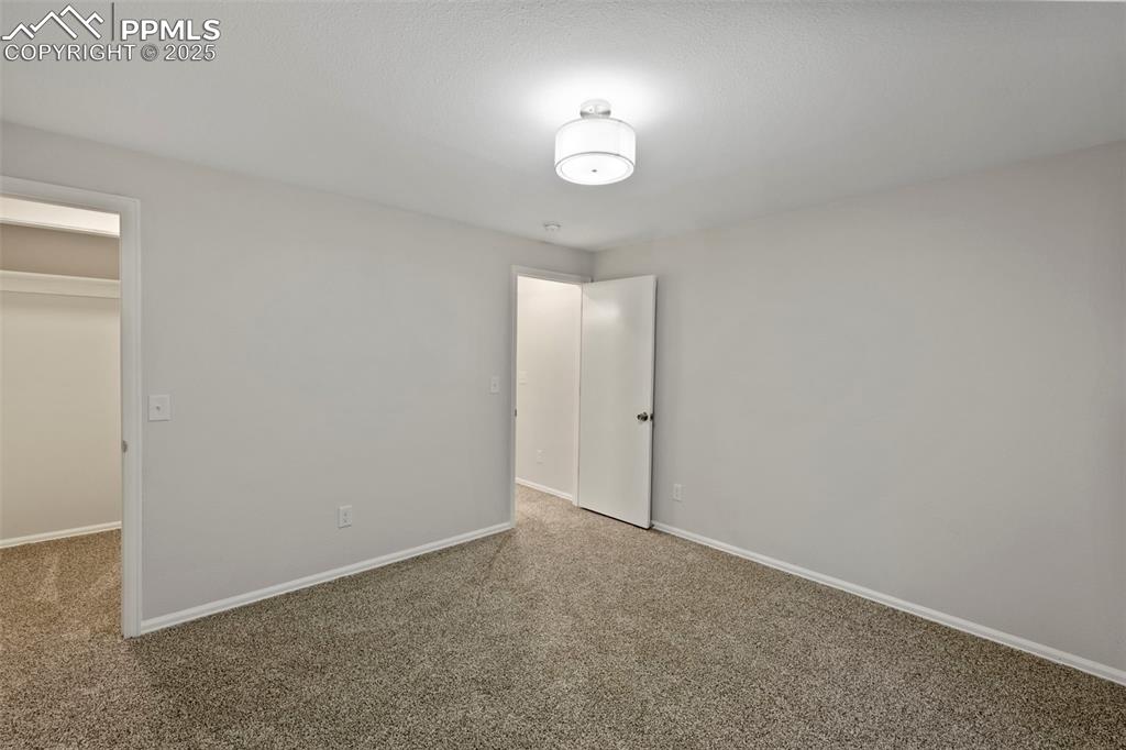 Image 28 of 39: Downstairs, two additional bedrooms offer plush carpet, walk-in closets, an