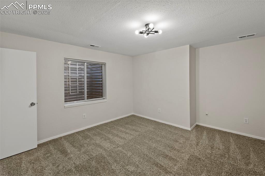 Image 29 of 39: Downstairs, two additional bedrooms offer plush carpet, walk-in closets, an