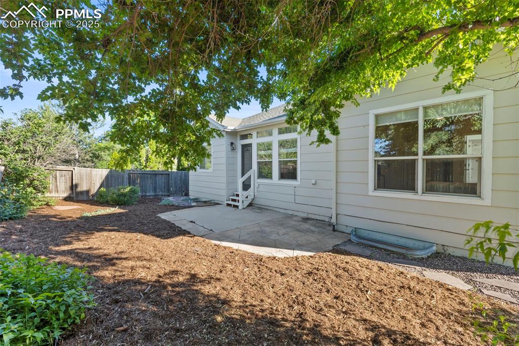 Image 35 of 39: Out back, a fenced yard with a patio and private gate creates the perfect c