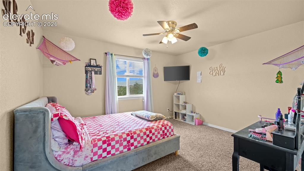 Image 21 of 41: Carpeted room featuring a ceiling fan with light fixture, a window with bli