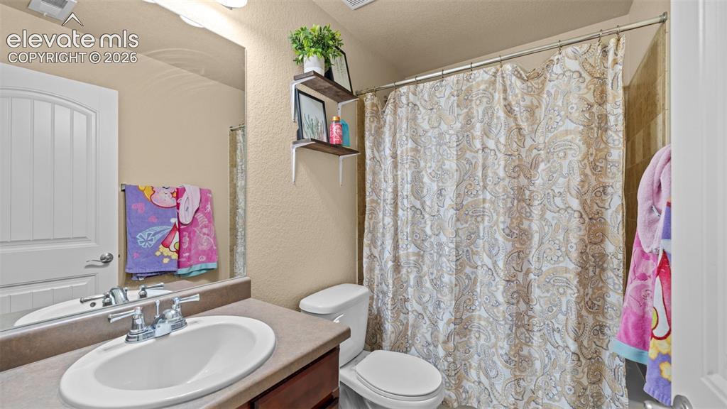 Image 24 of 41: Carpeted room with a single window featuring blinds, textured walls, and a