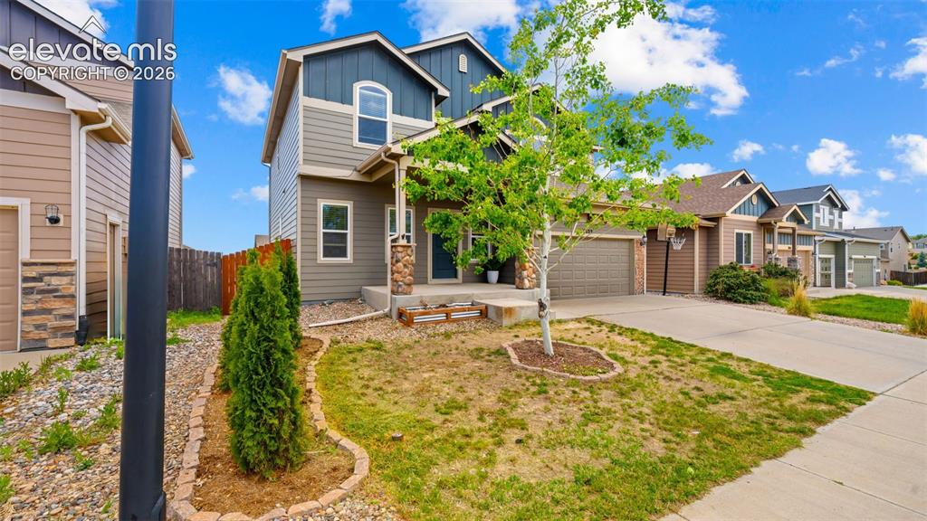 Image 37 of 41: Two-story residence featuring a covered entry, stone column accents, and a