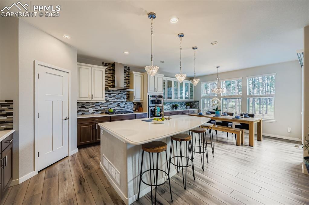 Image 15 of 50: Kitchen with tasteful backsplash, a breakfast bar area, hanging light fixtu