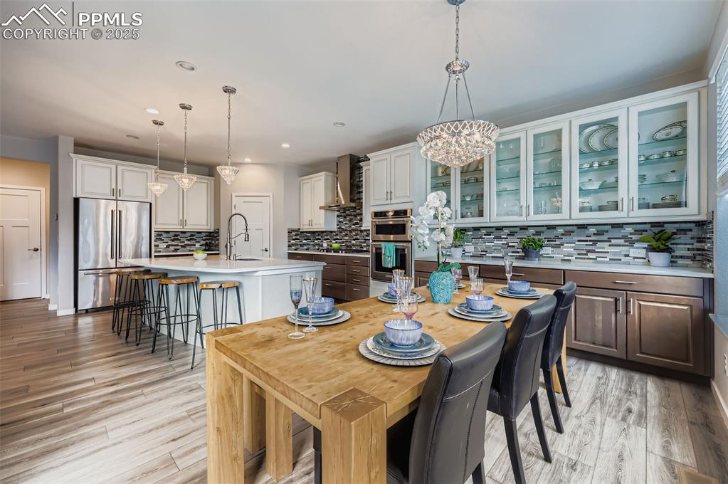 Image 17 of 50: Dining area featuring light wood-style floors, recessed lighting, and a cha