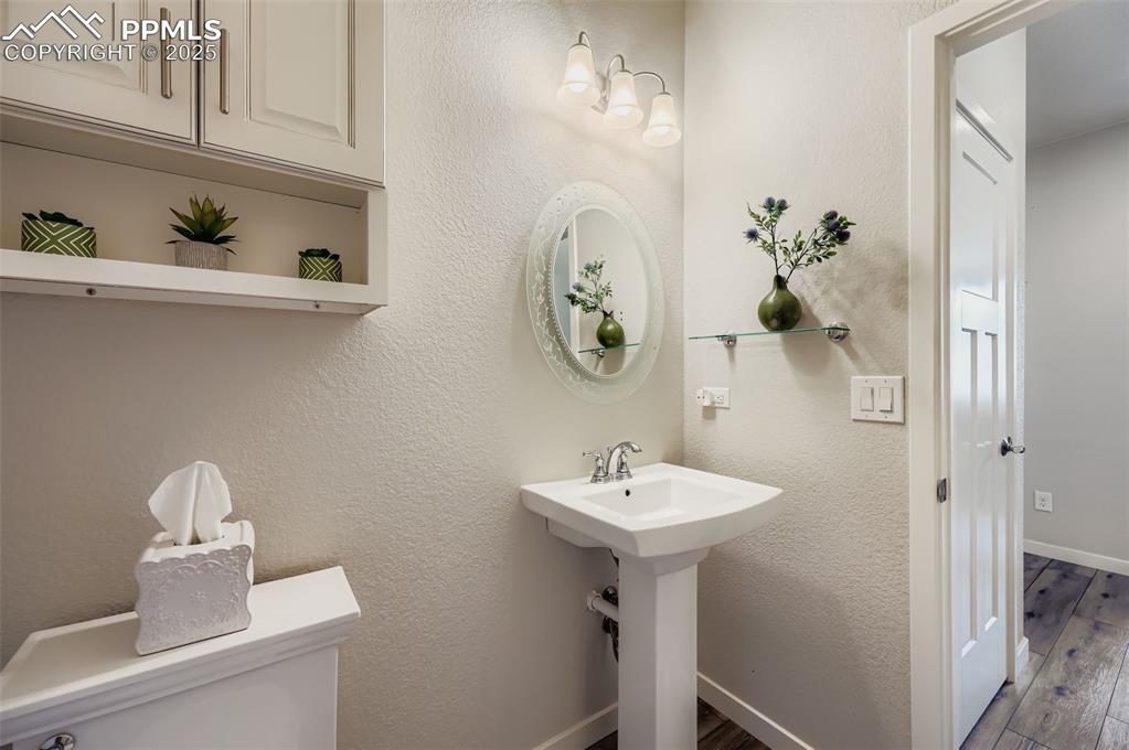 Image 19 of 50: Bathroom with a textured wall and dark wood-type flooring