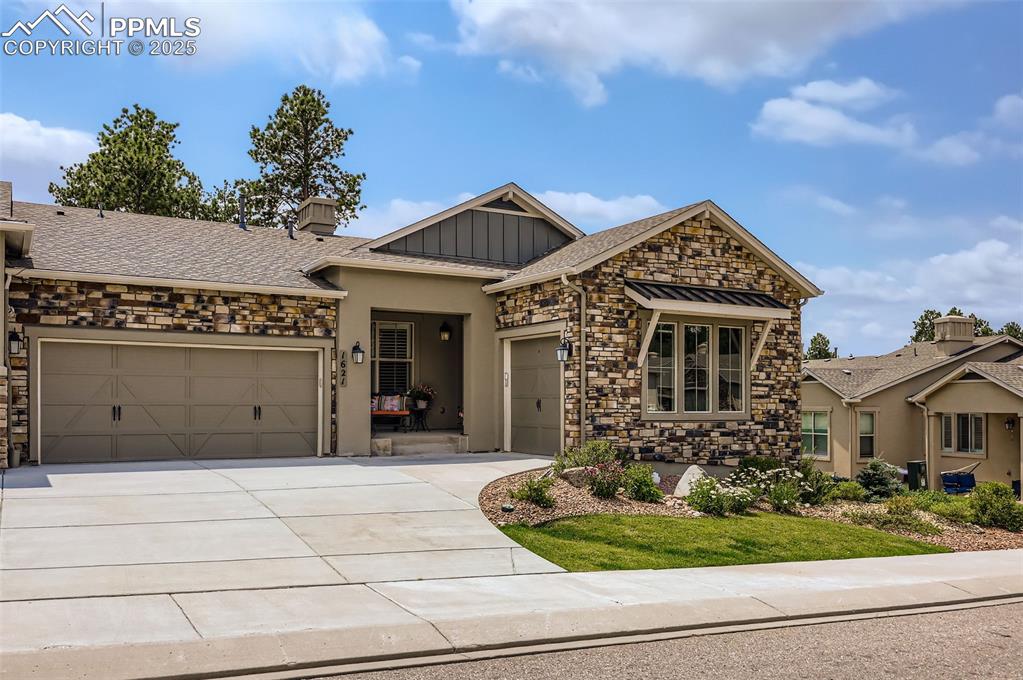 Image 2 of 50: View of front of property featuring stone siding, driveway, and an attached