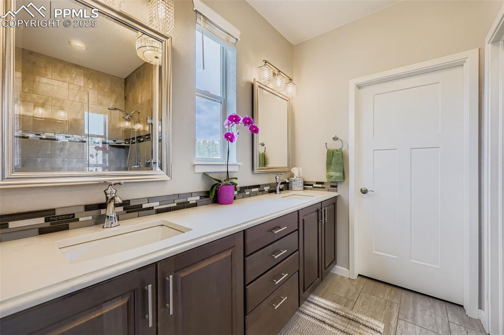 Image 23 of 50: Bathroom with double vanity, wood finish floors, and tiled shower