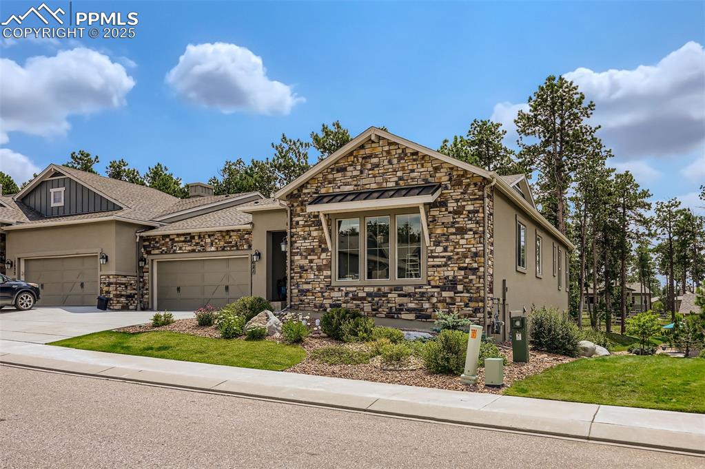 Image 3 of 50: View of front facade with stone siding, stucco siding, concrete driveway, a