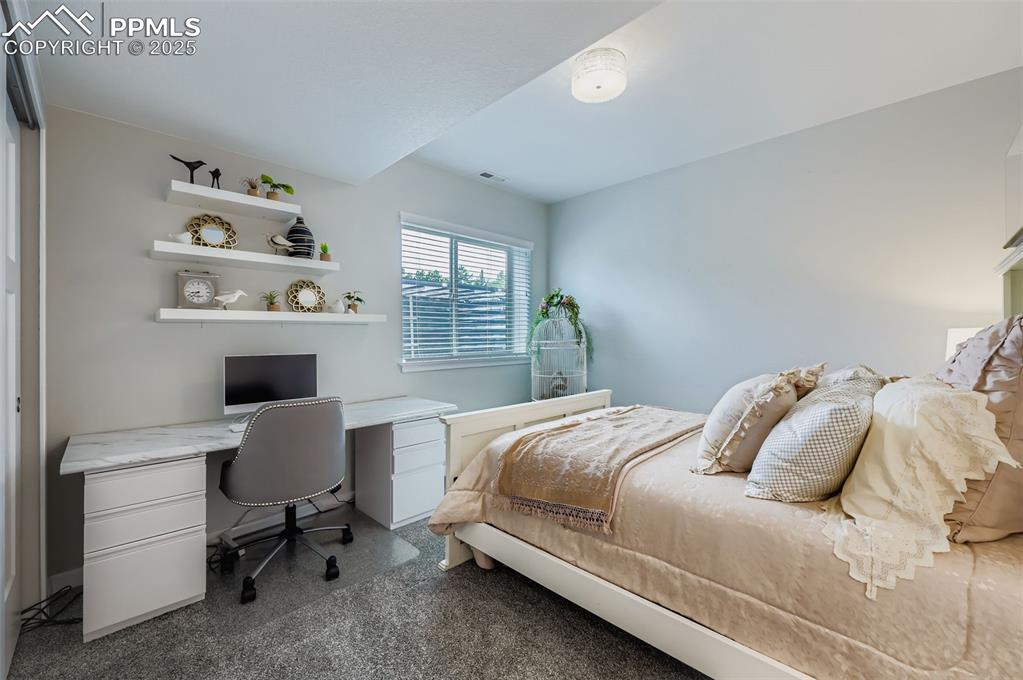 Image 35 of 50: Bedroom with a desk and dark carpet