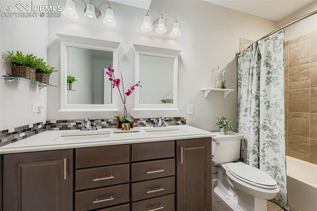 Image 36 of 50: Full bathroom with double vanity, shower / tub combo with curtain, a textur