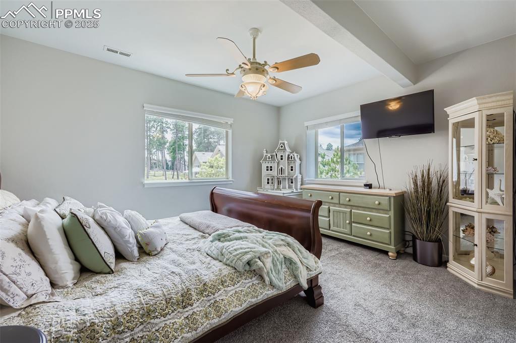 Image 40 of 50: Carpeted bedroom featuring beam ceiling and ceiling fan