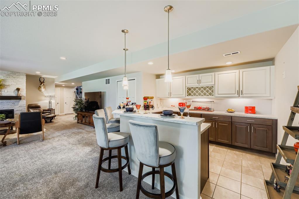 Image 44 of 50: Kitchen featuring hanging light fixtures, white cabinets, a breakfast bar, 