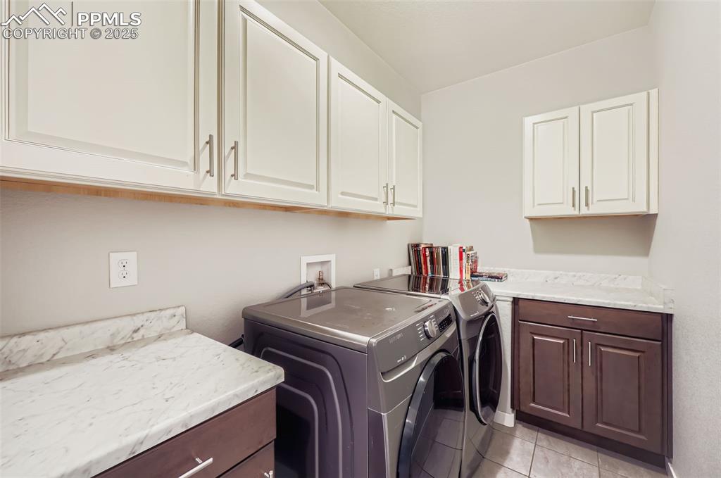 Image 46 of 50: Laundry area with light tile patterned floors, washer and clothes dryer, an