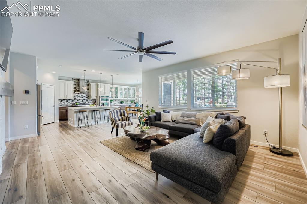 Image 8 of 50: Living area featuring ceiling fan and light wood-style flooring