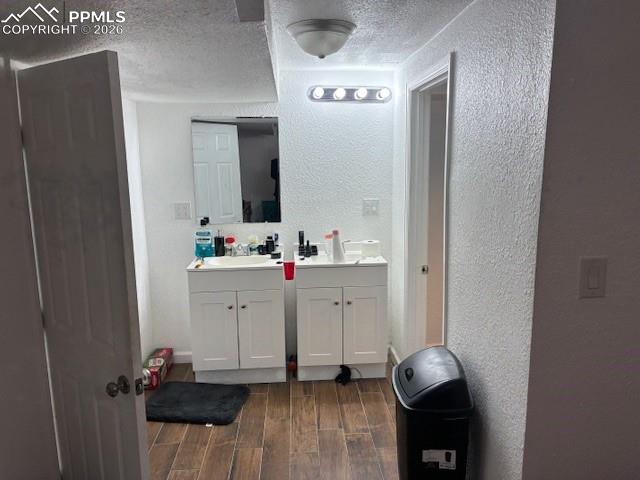 Image 12 of 17: Bathroom with a textured wall, wood tiled floors, vanity, and a textured ce