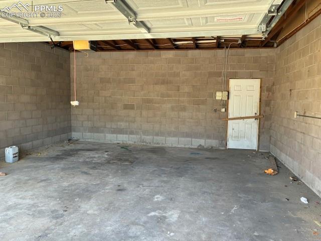 Image 24 of 24: Garage featuring concrete block wall and a garage door opener