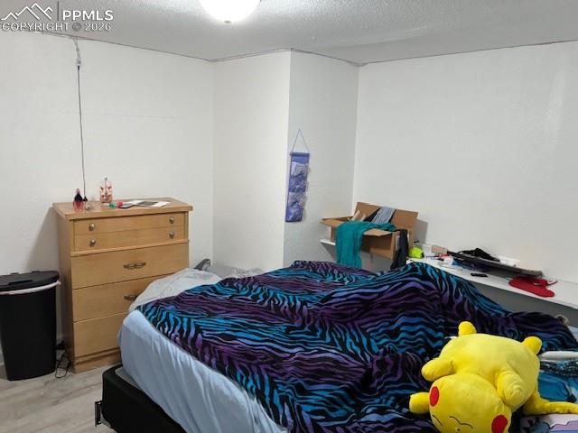 Image 9 of 17: Bedroom with a textured ceiling and wood finished floors