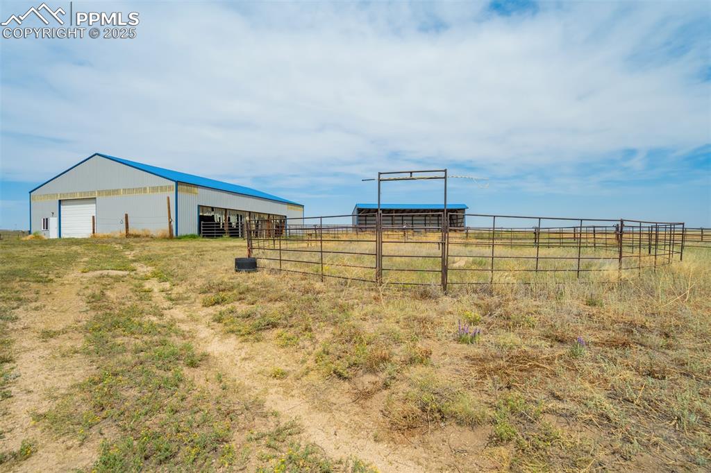 Image 42 of 50: View of yard featuring a pole building, an outdoor structure, and a rural v
