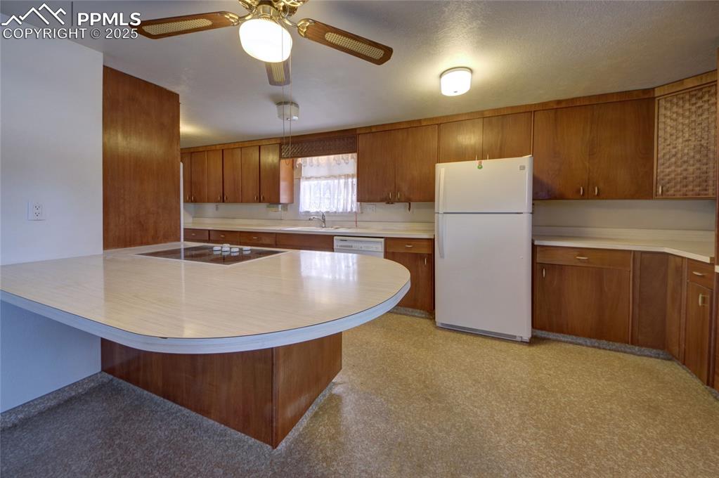 Image 13 of 37: Kitchen with white appliances, brown cabinets, light countertops, a ceiling