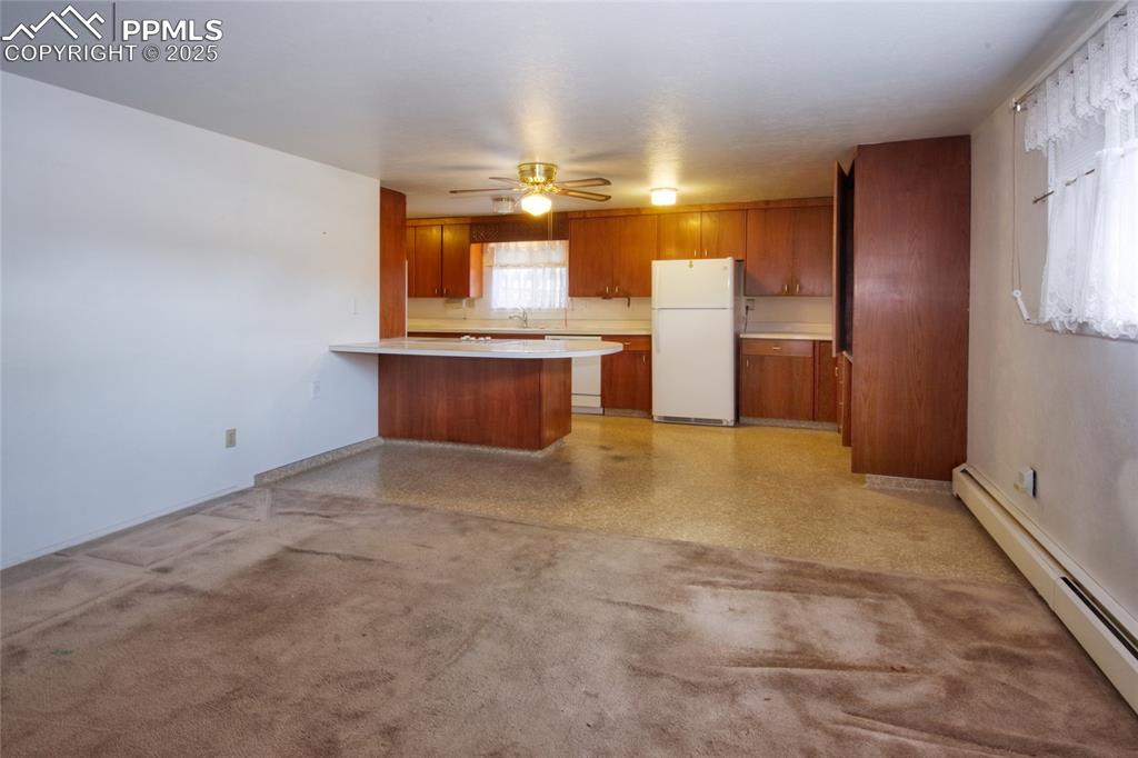 Image 14 of 37: Kitchen featuring baseboard heating, a peninsula, white appliances, brown c