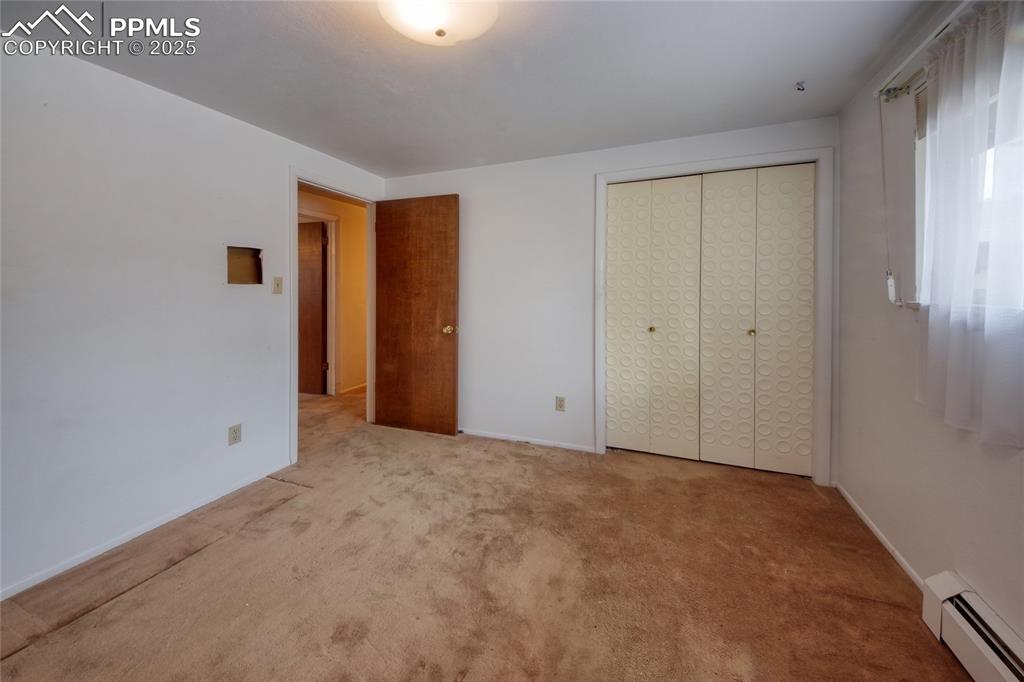 Image 22 of 37: Unfurnished bedroom featuring a baseboard radiator, carpet floors, and a cl