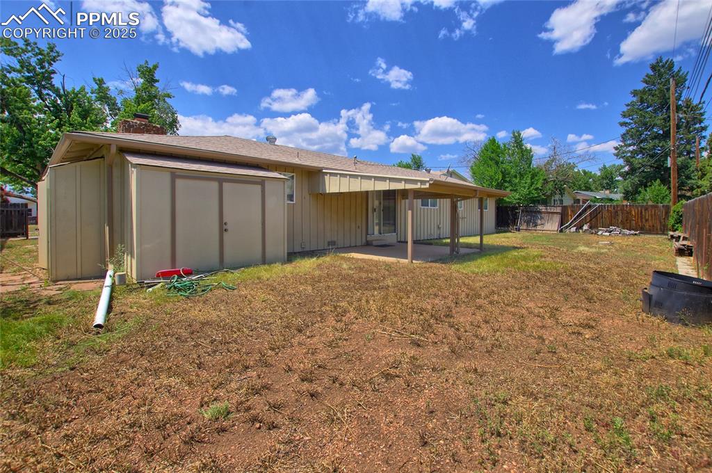 Image 33 of 37: Back of property with a fenced backyard, a patio, a chimney, and a shed