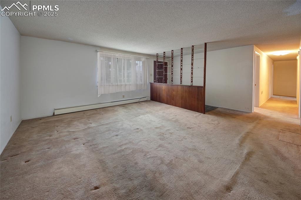 Image 4 of 37: Unfurnished living room featuring baseboard heating, a textured ceiling, an