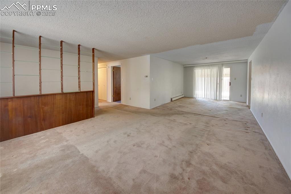 Image 5 of 37: Unfurnished room with carpet floors, baseboard heating, and a textured ceil