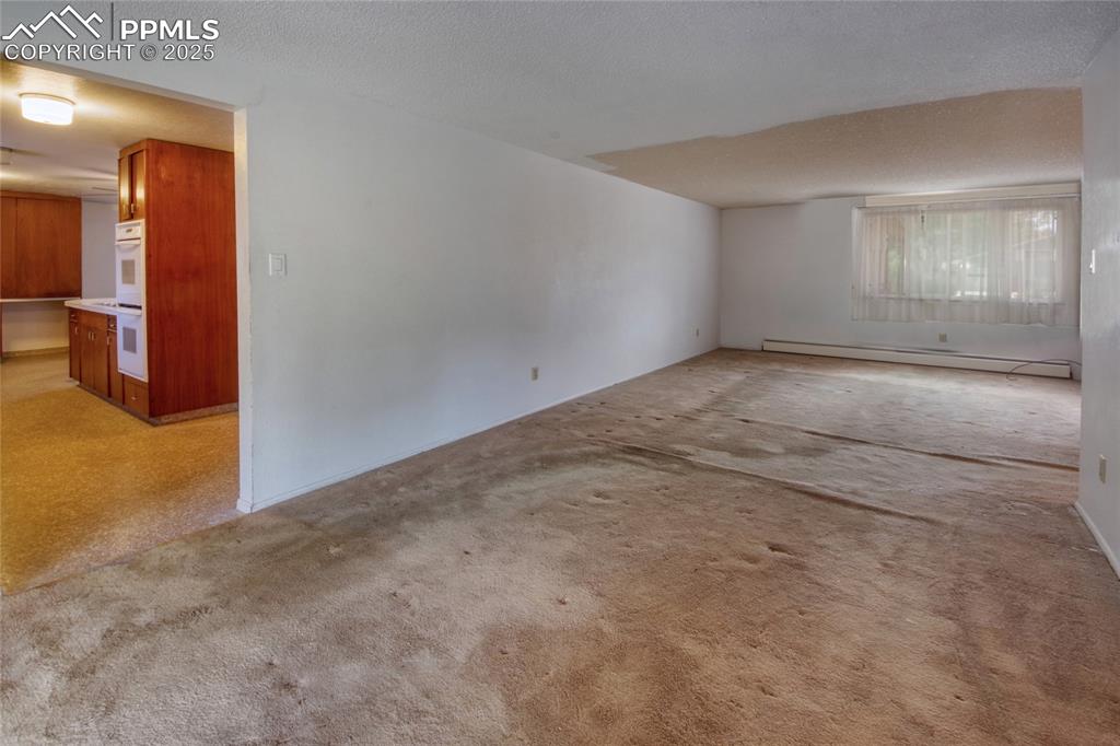 Image 6 of 37: Spare room with light colored carpet and a baseboard heating unit