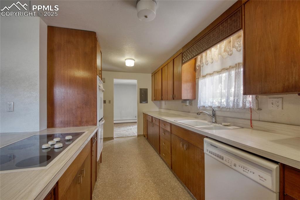 Image 8 of 37: Kitchen with brown cabinets, white appliances, light countertops, light flo