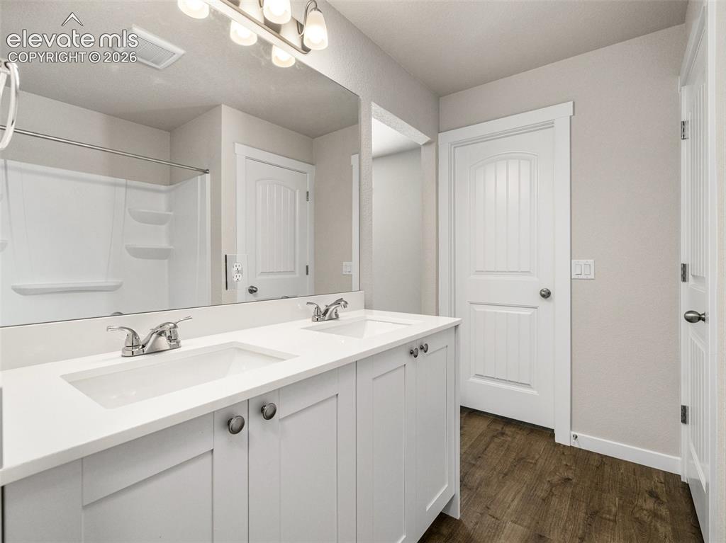 Image 12 of 30: Dual vanity with white shaker-style cabinetry, chrome hardware, and integra