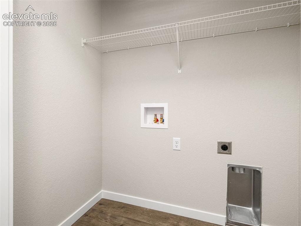 Image 13 of 30: Laundry area featuring a wire shelf, wall-mounted connections, and wood-fin