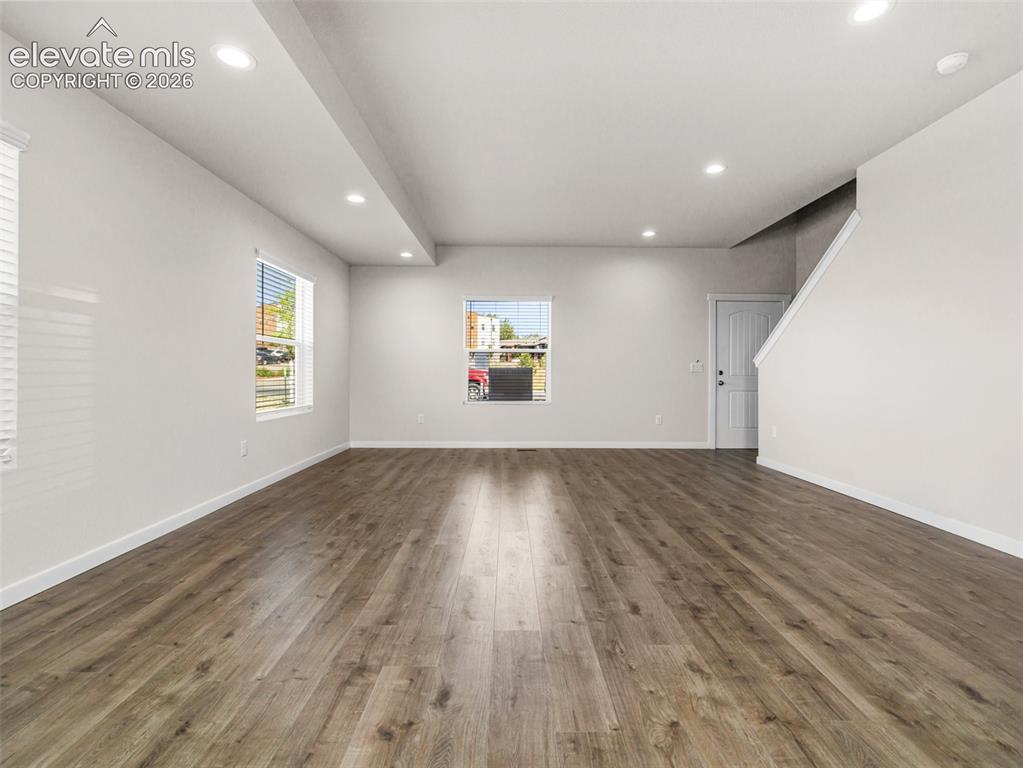 Image 16 of 30: Spacious room with wood-finish flooring, recessed lighting, and multiple wi