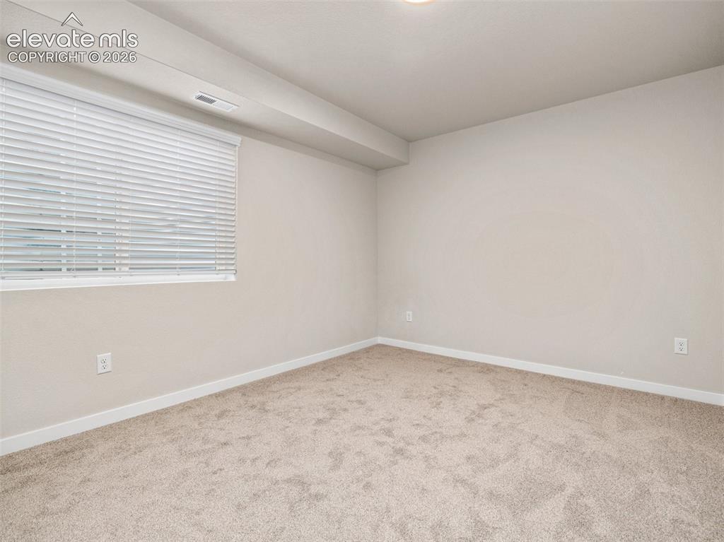 Image 24 of 30: Neutral-toned carpeting, white window blinds, and recessed lighting