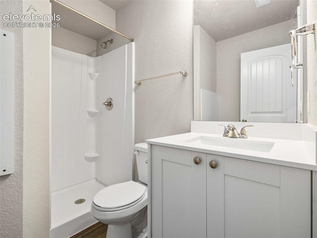 Image 26 of 30: White vanity with integrated sink, brushed nickel faucet, and frameless mir